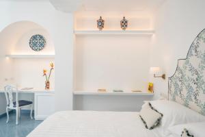 a white bedroom with a bed and a desk at Boutique Hotel Casa Mariantonia in Anacapri