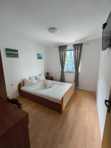 een slaapkamer met een groot bed en een raam bij Apartmani Barešić in Podgora
