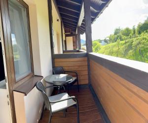 einen Balkon mit 2 Stühlen, einem Tisch und einem Fenster in der Unterkunft Готель-ресторан Два Леви in Slawske