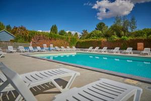 a swimming pool with lounge chairs and a swimming pool at Bungalow cosy pour 6 personnes in Ivry-la-Bataille