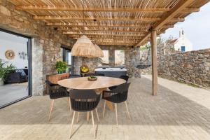 an outdoor patio with a wooden table and chairs at Mykonos Cottage in Ano Mera