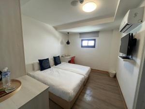 Habitación pequeña con cama y TV. en Hotel Huru House, en Taichung