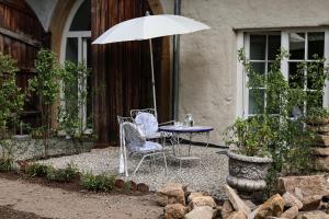 a table and chairs under an umbrella in a yard at Historische Mühle von Cramm in Ballrechten-Dottingen