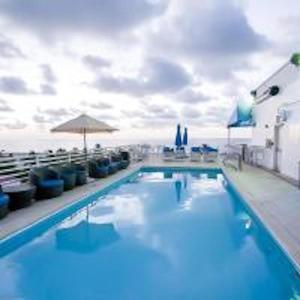 a large swimming pool with chairs and an umbrella at Congress Ocean Drive in Miami Beach