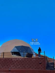 MARS LUXURY CAMP WADi RUM في وادي رم: رجل يقف أمام مبنى سكني
