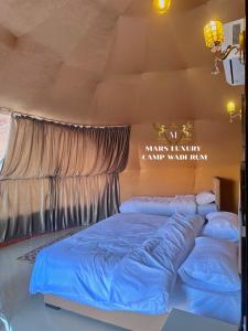 um quarto com 2 camas em frente a uma parede em MARS LUXURY CAMP WADi RUM em Wadi Rum