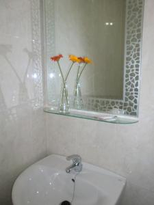 baño con lavabo, espejo y jarrones con flores en Hostal Santa Ana, en San José de La Rinconada