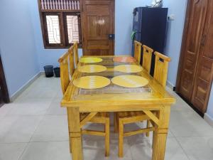 a wooden table with four yellow plates on it at Moorthy House in Kankesanturai