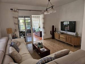 a living room with a couch and a flat screen tv at Casa Golden in Caleta De Fuste
