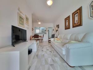ein Wohnzimmer mit einem weißen Sofa und einem Flachbildfernseher in der Unterkunft Plaza Riviera - Módulo 6 - 2 Quartos - 300 metros da praia in Riviera de São Lourenço