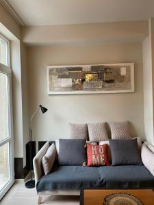 a living room with a blue couch and a painting at Chavchavdze VAKE - 1BR Apartment in Tbilisi City