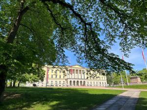 un grand bâtiment blanc dans un parc arboré dans l'établissement National Theater Dormitory Mixed, à Oslo