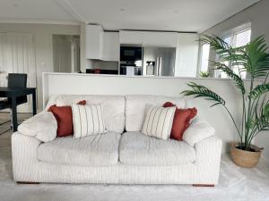 ein weißes Sofa mit zwei Kissen im Wohnzimmer in der Unterkunft Serenity Lodge, Riverside with Free Parking in Christchurch