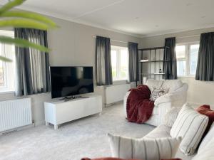 a living room with a white couch and a television at Serenity Lodge, Riverside with Free Parking in Christchurch