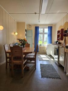 a dining room with a table and chairs and a kitchen at Fokhol Gård Gjestehus in Stange