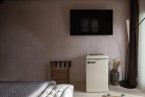 a small refrigerator in a room with a tv on the wall at Kynthia Hotel - Adults Only in Kalogria