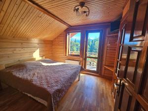 um quarto com uma cama num quarto de madeira com uma janela em Barvy Karpat em Slavske