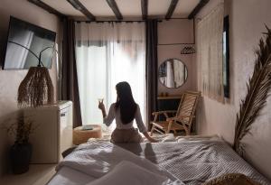 a woman sitting on a bed holding a glass of wine at Kynthia Hotel - Adults Only in Kalogria