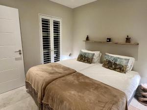 a bedroom with a large bed with two pillows at Dolphin Beach Cabana in Table View