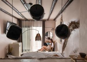 a woman sitting in a chair reading a book in a bedroom at Kynthia Hotel - Adults Only in Kalogria