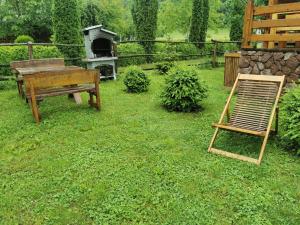 a wooden bench and a grill in a yard at Wooden House Ripac in Bihać