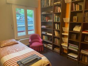 um quarto com uma cama, uma cadeira e prateleiras de livros em La maison du lac em Lutry