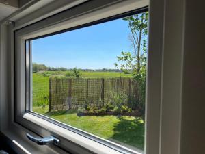 a window with a view of a field and a fence at Chalet De Miranda in Midsland