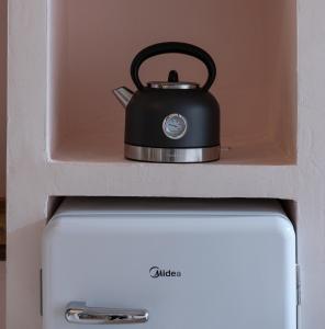a black tea kettle sitting on top of a refrigerator at Kynthia Hotel - Adults Only in Kalogria