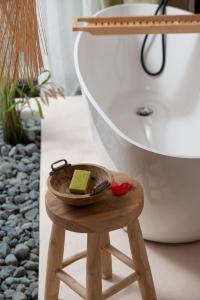 a wooden stool with a plate of soap on it next to a bath tub at Kynthia Hotel - Adults Only in Kalogria