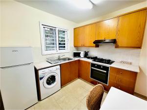 a kitchen with wooden cabinets and a washer and dryer at KAMILA 5 in Oroklini