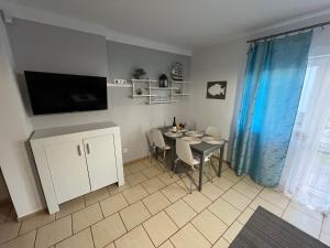 a dining room with a table and a tv on the wall at Apartament Nostalgia in Gąski