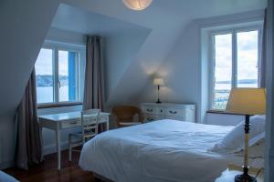 Un dormitorio con una cama, un escritorio y ventanas. en Villa Penn Ar Bed, en Crozon