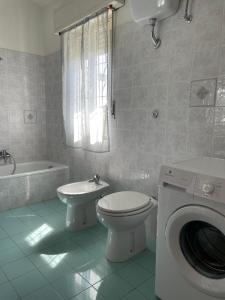 a bathroom with a toilet and a sink and a washing machine at Su Tostobiu in San Nicolò dʼArcidano +29 photos