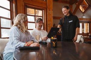 a group of people sitting around a table with a man standing at Emerald Lake Lodge in Field