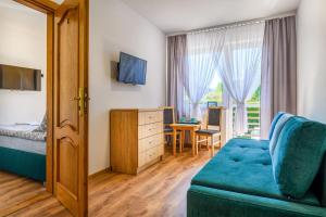 ein Hotelzimmer mit einem blauen Sofa und einem Schlafzimmer in der Unterkunft Dom Wypoczynkowy Arka in Jastrzębia Góra