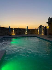 a swimming pool with green lights in the water at Maison Ayachi in El Aadamna