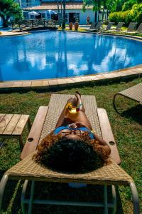 a woman laying on a bench with a drink in her face at Baía Branca Beach Resort in Tamandaré