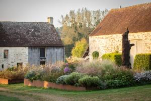 an old stone house with a garden in front of it at La Queurie in La Courbe