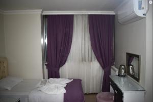 una camera d'albergo con letto e tende viola di Kümbet Hotel a Istanbul Altre 4 foto