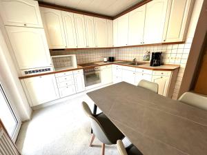 a kitchen with white cabinets and a table and chairs at Kulturmensch Oberhausen mit Balkon in Oberhausen +4 photos