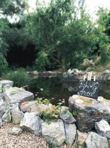 una señal sentada en algunas rocas junto a un estanque en Casă din povești în mijlocul naturii! en Arad
