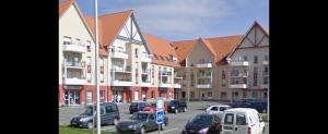 a parking lot with cars parked in front of a building at Le clos des Boucaniers in Berck-sur-Mer