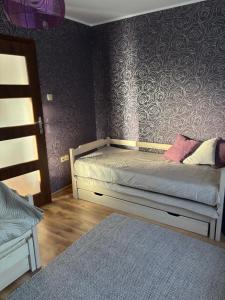 a small bedroom with a bed and a purple wall at Raj z haczykiem in Grzmięca +4 photos