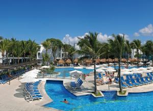 a pool at a resort with chairs and umbrellas at Riu Yucatan - All Inclusive in Playa del Carmen