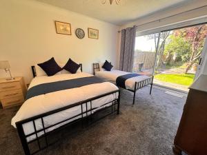1 dormitorio con 2 camas y ventana grande en High Trees Guest House Gatwick, en Hookwood
