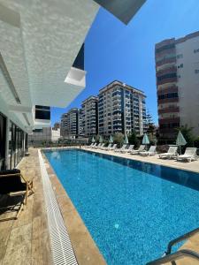 a large swimming pool with lounge chairs and buildings at SA Apartments! 1bd Flat 300m to the Beach in Alanya