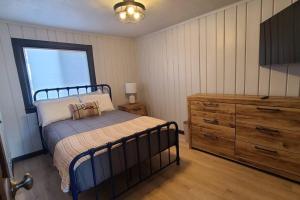 a bedroom with a bed and a dresser and a window at The Northern Lights Cottage in Columbia Falls