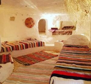 a room with two beds and a rug at Gite Douiret in Ad Duwayrāt