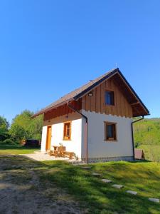 mały biały dom z drewnianym dachem w obiekcie Horná chata u Bratrikov w mieście Haligovce