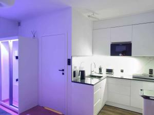 a kitchen with white cabinets and a purple door at KIWI Apartament in Muszyna
